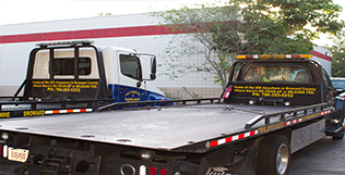 Rearview of two J&S flatbed tow trucks